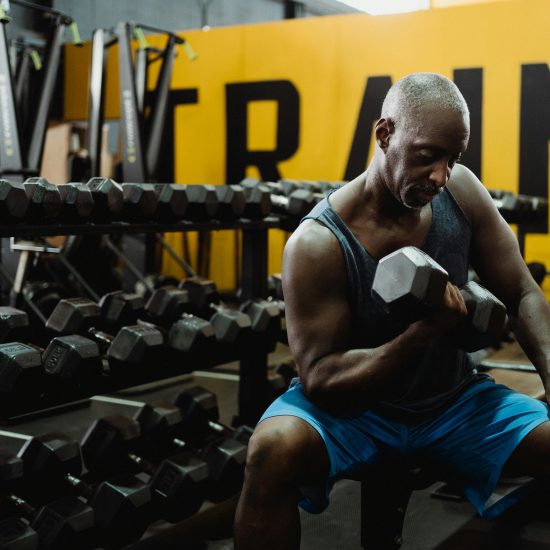 Adult man performing dumbbell curls in a modern gym, emphasizing strength and fitness.